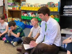 man praying with students in classroom